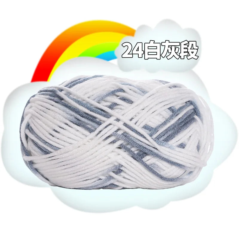 A ball of light gray and white milk cotton blend yarn is shown against a background with a rainbow and cloud graphic.