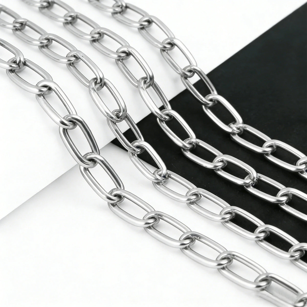 Silver stainless steel chain links laid out on a dark surface.