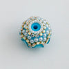 A round, light blue bead embellished with white pearls and gold-toned rhinestones.