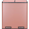 A rectangular, matte pink recycling trash can with a dark trim and two visible openings on the bottom.