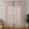 Pink ruffled French lace sheer curtains with floral embroidery hanging in a window.