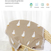 A beige cotton baby swaddle blanket with a white duck cartoon print is displayed in a wicker basket.