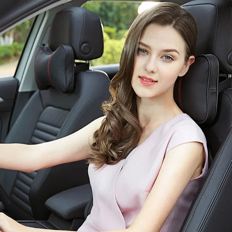 A young woman sits in a car seat, wearing a light pink top, with the PU leather headrest pillow and seatbelt shoulder pad set
