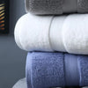 A stack of folded bath towels in shades of gray, white, and blue.