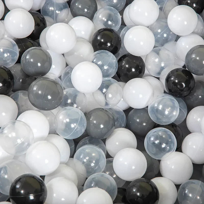 A close-up view of a large pack of colorful plastic ball pit balls in various shades of black, white, and translucent gray.