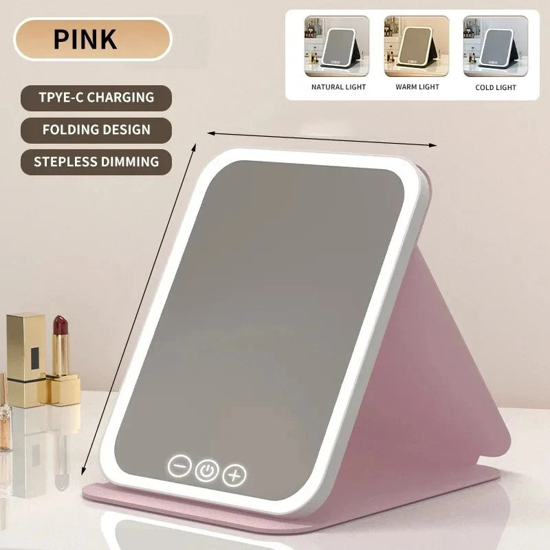 A pink portable touch vanity mirror with customizable natural, warm, and cold LED lights is shown on a surface.