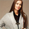 A woman wearing a light gray knitted sweater with decorative vintage rotating clips.
