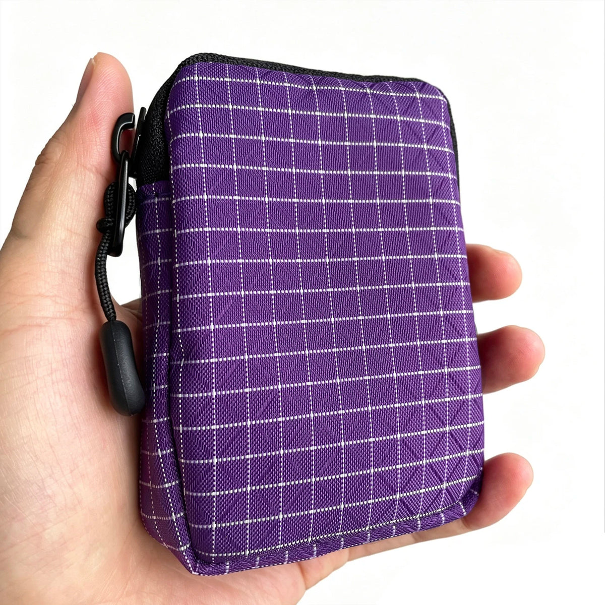 Purple plaid compact EDC utility pouch with black lining and zipper on a hand