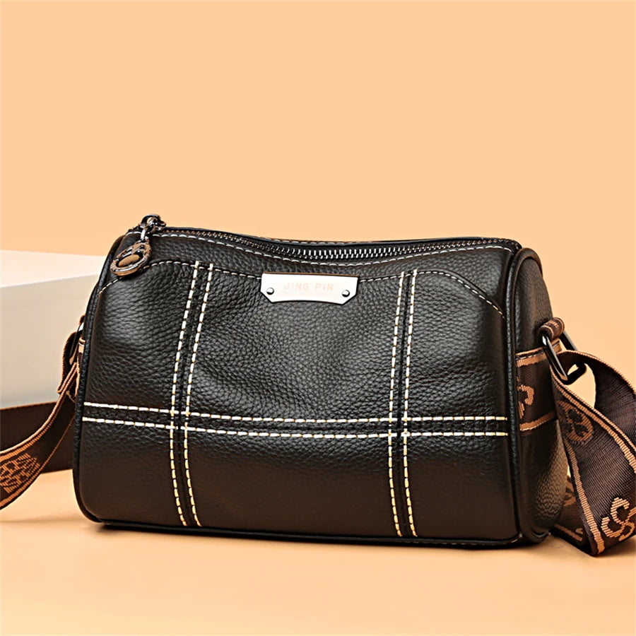A black vintage genuine leather women's shoulder bag with tan accents and stitching, shown in a studio setting.