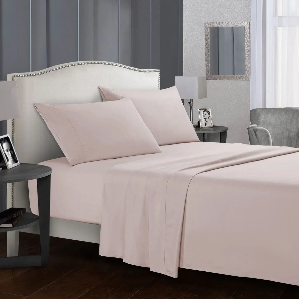 A light pink bedding set featuring a fitted sheet, flat sheet, and pillows on a bed in a modern bedroom.