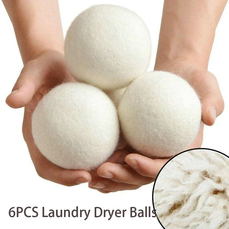 Three white natural wool dryer balls held in a person's hands.