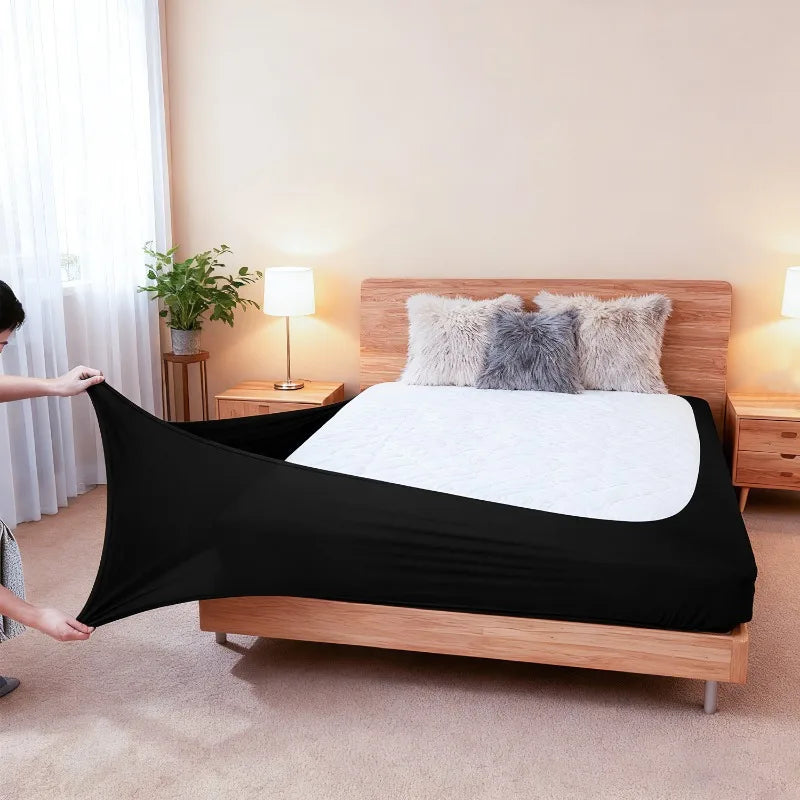 Black stretch-fit box spring cover with an elastic edge placed on a wooden bed frame.