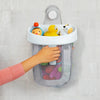 A hand is placing a white hanging bath toy storage bag with a light gray mesh onto a tile wall.
