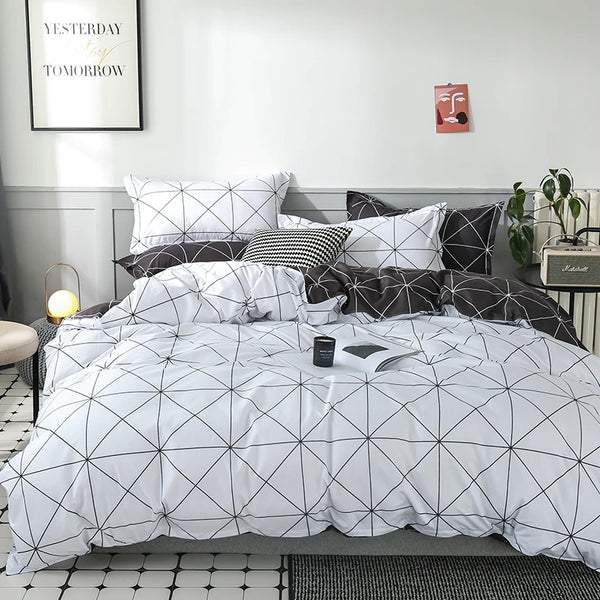 A white duvet cover set with a black geometric pattern displayed on a bed with gray bedding and pillows.