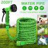 A bright green expandable water pipe or hose with a spray nozzle is shown in an outdoor garden setting.
