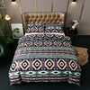 A patterned duvet cover set featuring geometric stripes in purple, pink, and black on a bed with a tufted headboard.