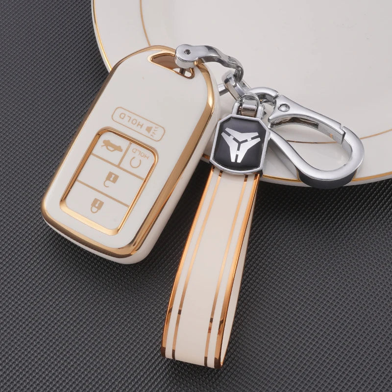 A white TPU protective key case with gold accents and a silver keyring attached to a leather strap.