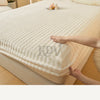 A close-up of a white, textured fitted sheet with faux fur trim on a bed, showing the fabric texture and softness.