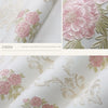 Close-up of pink and green floral wallpaper featuring detailed carved designs on a white background.