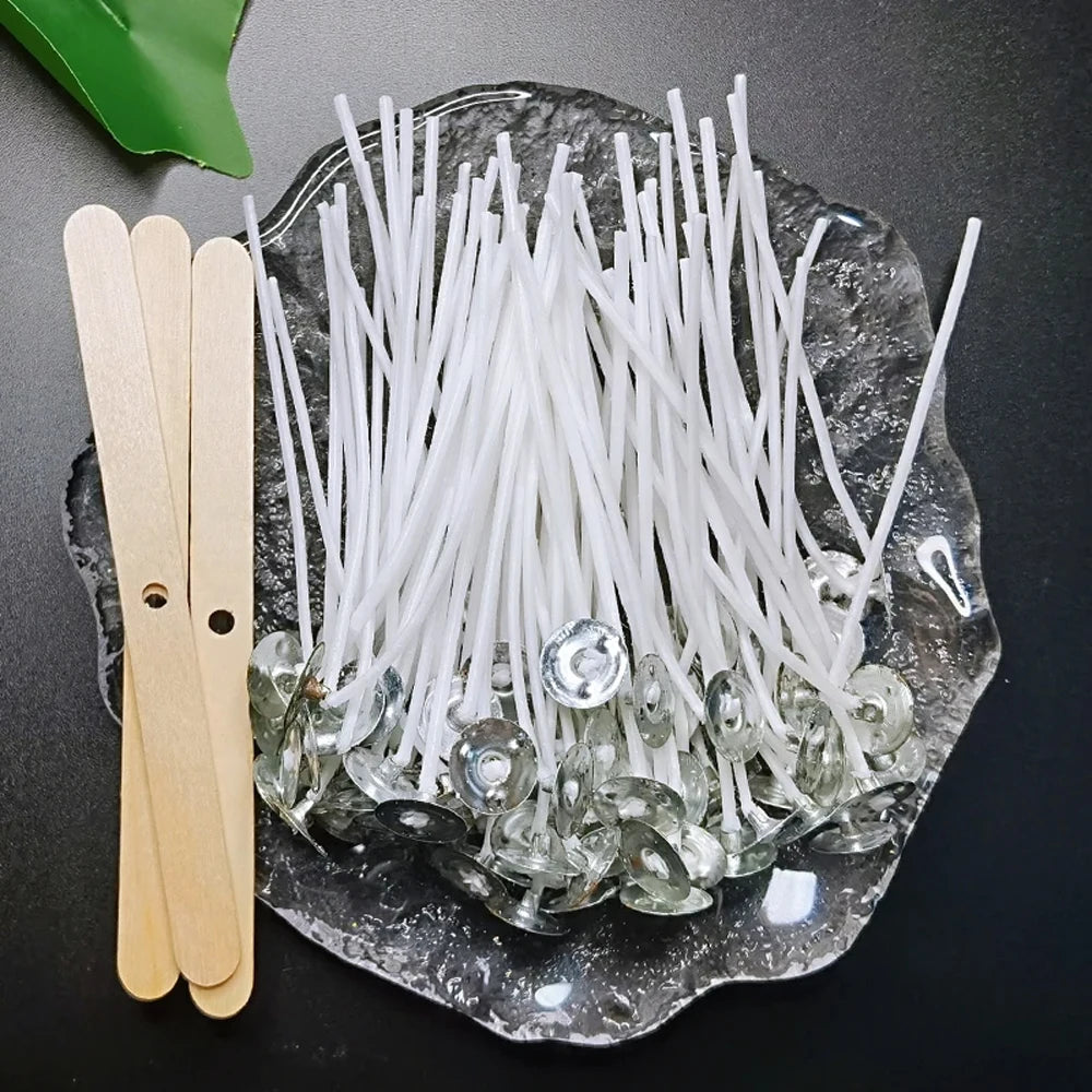 A collection of white cotton candle wicks with metal stands is displayed on a dark surface next to a wooden stand.