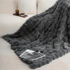 Dunkelgraues, weiches Kunstfell-Kaninchen-Fleece-Decke über einem weißen Sofa mit Glas- und Holztablett.
