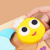 A hand is holding a yellow puzzle piece shaped like a smiling bee, part of a wooden learning toy set.