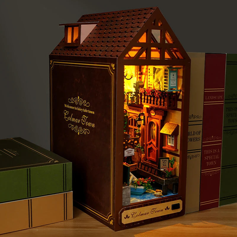 A miniature DIY book nook kit featuring a detailed fairy tale town scene built into a wooden house structure.