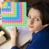 A colorful 12x12 multiplication practice math game board showing the equation 5x5=25, held by a child.