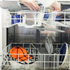 A white plastic hat washing cage set for baseball caps is being loaded into a dishwasher.