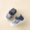 A pair of gray and pink knitted baby shoes with a soft sole are shown on a light background.