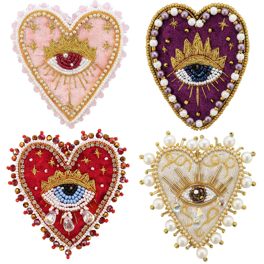 Two heart-shaped patches featuring sparkling beads and rhinestones, one pink and gold, the other purple and gold.