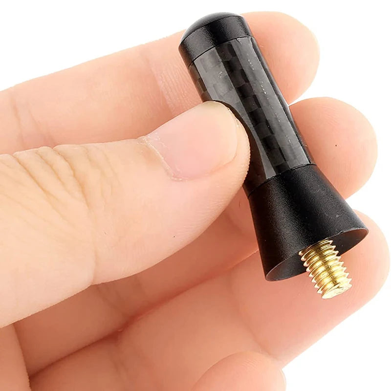A hand holds a black universal carbon fiber short radio antenna with a threaded base.