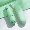 A light green compact 5-fold travel umbrella with a protective sleeve is shown on a white surface.