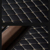 Close-up view of black quilted leather car floor mats with gold stitching.