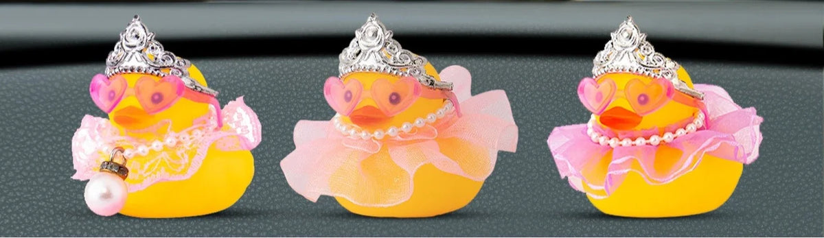 Three yellow rubber duck decorations adorned with princess crowns, sunglasses, and pearl necklaces.