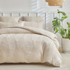 A beige embossed leaf pattern microfiber duvet cover set displayed on a bed with white headboard and natural light.