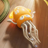 An orange interactive dancing octopus toy with light-up tentacles resting on a wooden floor.
