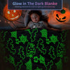 Ein Kind liegt unter einer leuchtenden Decke mit grünen Halloween-Designs, mit geschnitzten Kürbissen in der Nähe.