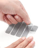 A hand is applying a self-adhesive window screen repair patch to a glass surface.