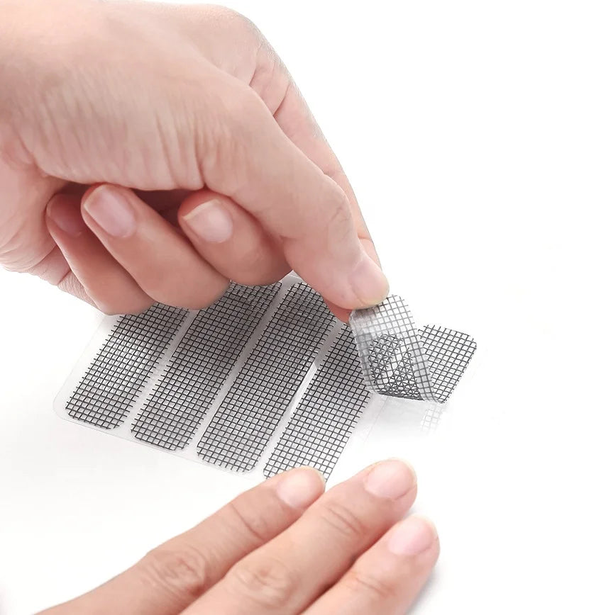 A hand is applying a self-adhesive window screen repair patch to a glass surface.