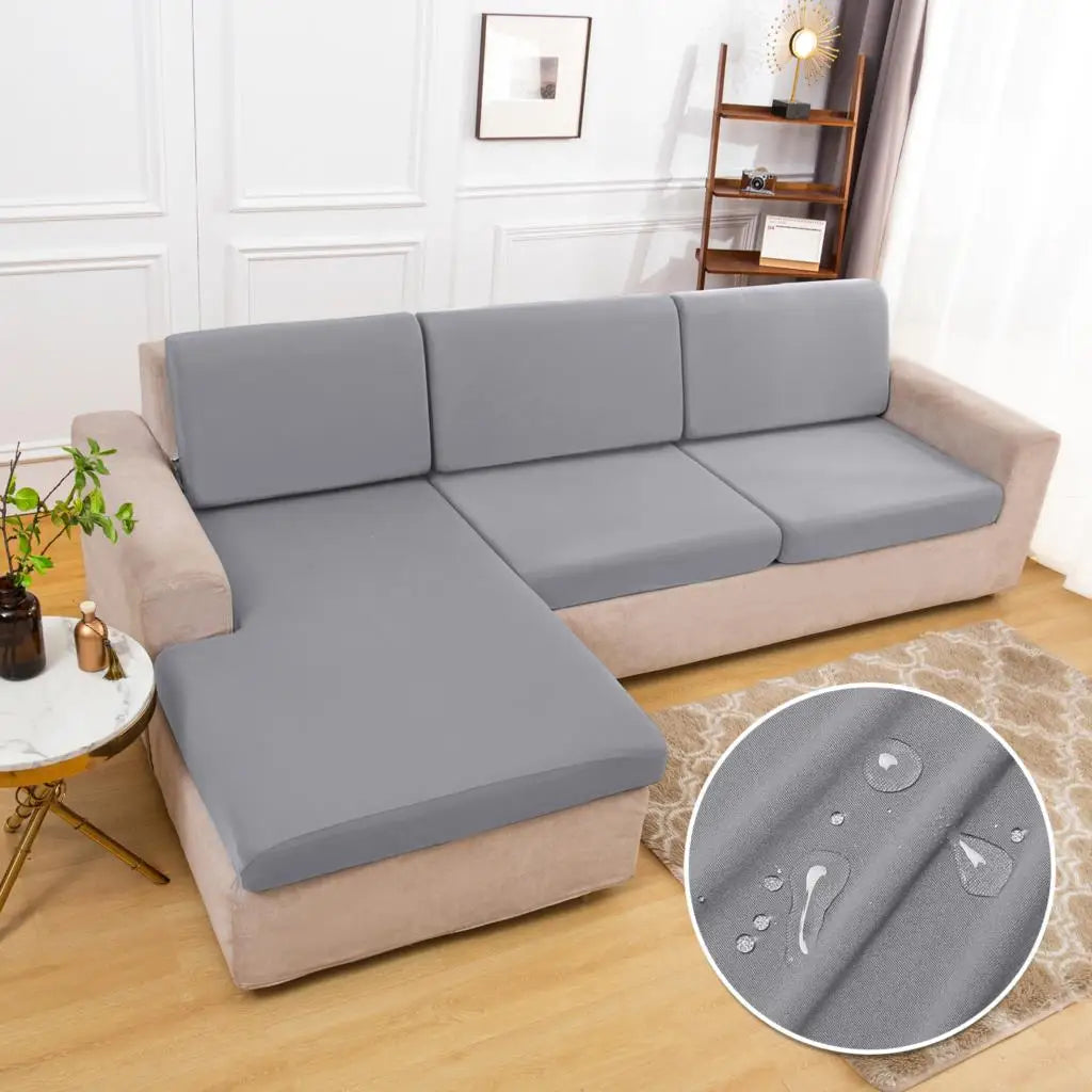 A light gray waterproof sofa cushion cover with an elastic edge shown on a beige sofa.