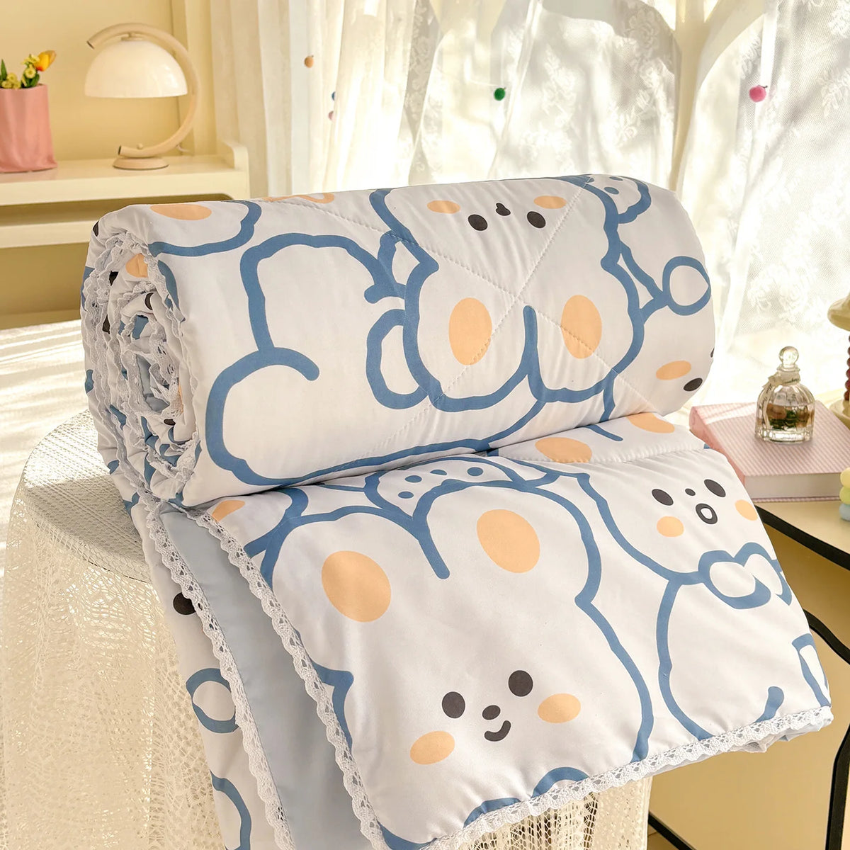 White comforter with blue and orange panda print featuring a lace trim on a white fabric.