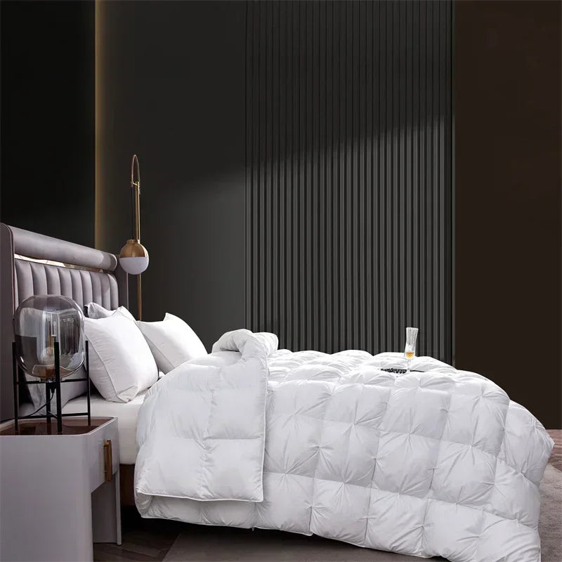 A white goose down comforter is displayed on a bed with gray bedding and dark wall paneling.