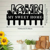 Black silhouette wall art featuring the name John and the phrase My Sweet Home with decorative iron hooks