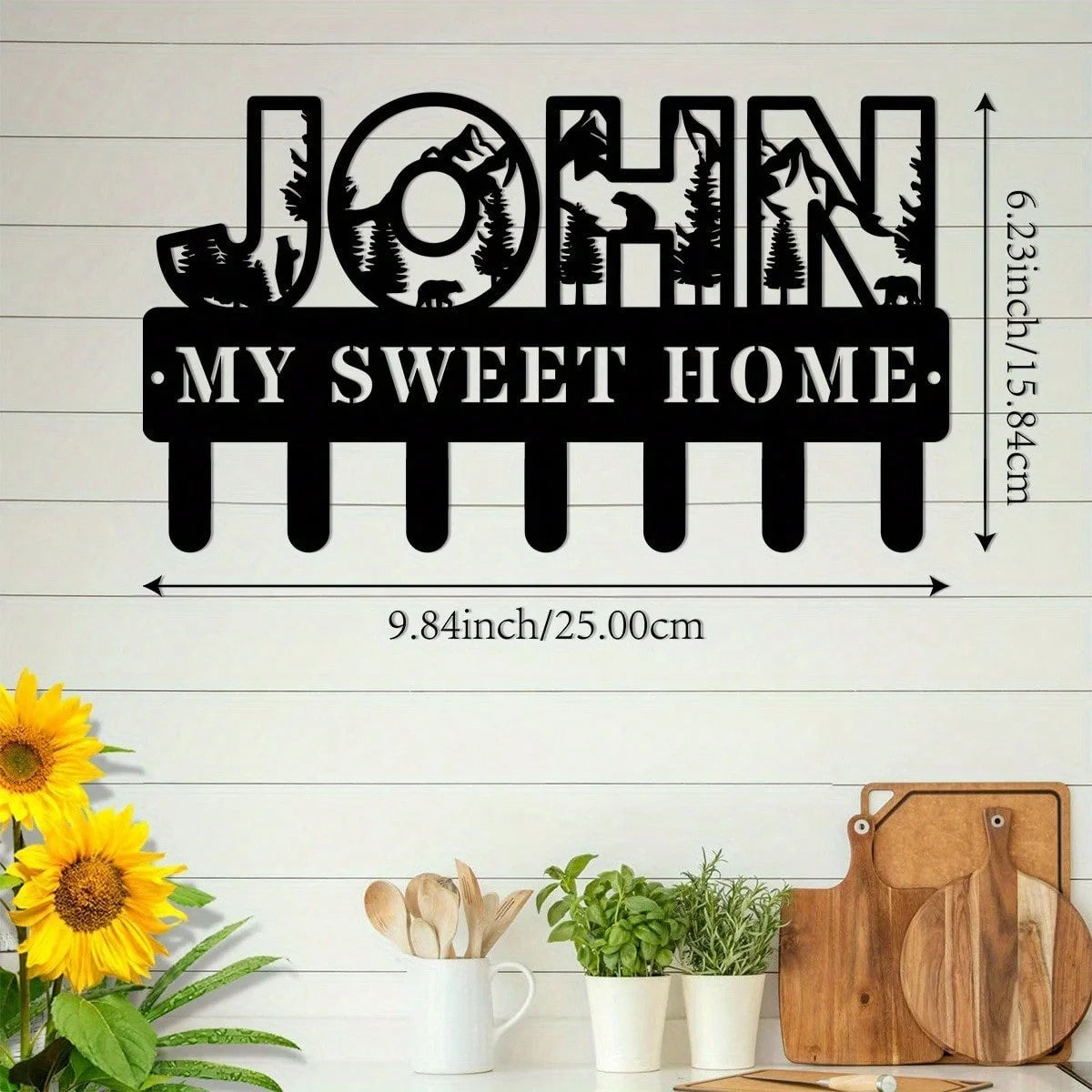 Black silhouette wall art featuring the name John and the phrase My Sweet Home with decorative iron hooks
