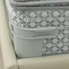 A close-up of a gray bedsheet corner tightener clip attached to a light-colored mattress cover.