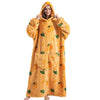 A woman wearing an oversized orange patterned wearable blanket hoodie with a hood and sleeves.