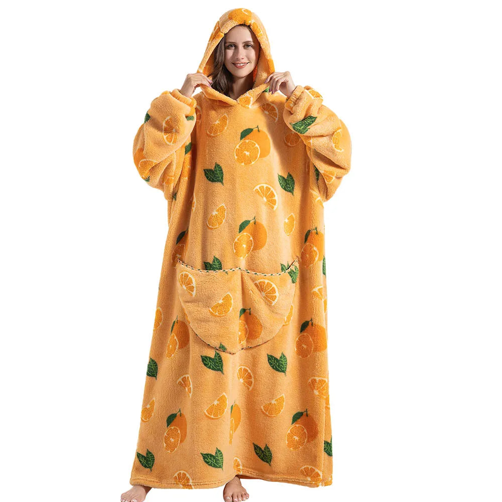 A woman wearing an oversized orange patterned wearable blanket hoodie with a hood and sleeves.