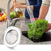 Stainless steel sink strainer mesh being used to rinse leafy greens in a kitchen sink.