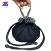 A black velvet dice storage pouch with a drawstring is held by a hand.